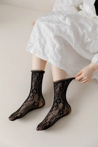 Close-up of black lace calf socks with floral mesh pattern and ruffled edges
