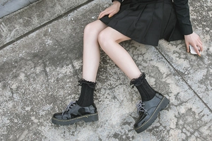 Close-up of black Lolita socks with mesh ruffles and classic black platform derby shoes