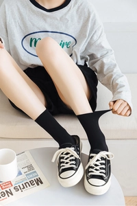 Detail of ribbed black crew socks showing fabric elasticity and casual canvas shoes style