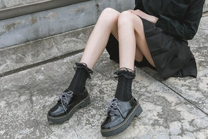 Detail of Lolita style black lace socks with heart pattern and shiny platform shoes