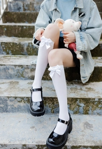 Close-up of white JK uniform socks with satin bows paired with Mary Jane shoes