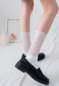 Gros plan de chaussettes blanches en dentelle ajourée avec bords festonnés et fleurs