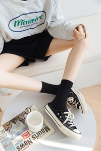 Detail of ribbed black mid-calf socks paired with canvas mules for a casual summer look