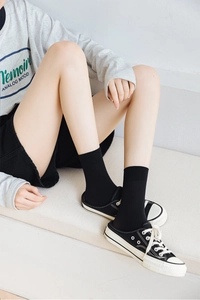 Detail of black vertical striped velvet socks with elastic non-slip cuffs on model