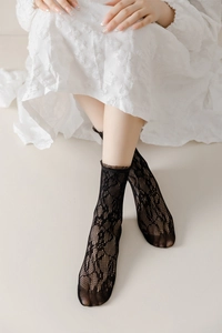 Detailed view of black lace mid-calf socks with delicate floral hollow mesh and ruffled cuffs