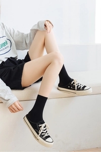 Detail of black canvas mule sneakers paired with matching crew socks for a casual look