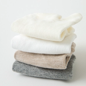 Detail view of four pairs of ribbed two-toe socks in white, beige, brown and grey tones