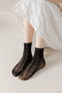 Close-up of black lace mesh socks with hollow diamond pattern and ruffled cuffs