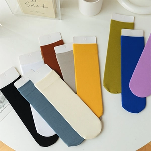 Close-up of colorful ribbed velvet crew socks in multiple shades on a minimalist setup