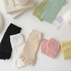Flat lay of colorful mesh five-toe socks with diamond hollow knit texture on white background