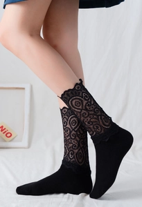 Détail de chaussettes hautes en dentelle noire avec motifs floraux et semelles en coton