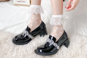 Détail de chaussettes en dentelle à cœurs avec mocassins plateforme en cuir verni noir