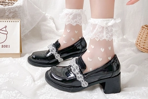 Détail de chaussures Mary Jane en cuir verni noir avec chaussettes en dentelle à cœurs