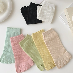 Macro view of assorted pastel five-toe socks with diamond mesh knitting and hollow lace edges