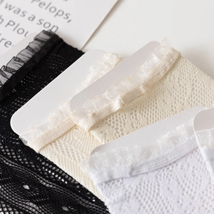 Close-up of white, beige and black lace mesh crew socks with ruffled scalloped edges