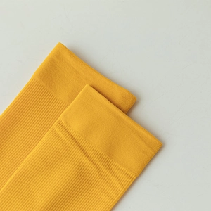 Detail of ribbed cuffs on bright yellow velvet socks showing elastic fabric texture
