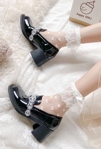 Détail de chaussettes en dentelle blanche à motifs cœurs et nœuds en soie sur mocassins