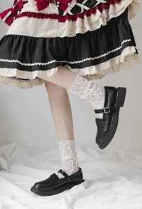 Detail of white lace mid-calf socks paired with black leather Mary Jane shoes in Lolita style