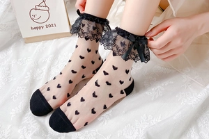 Détail de chaussettes en tulle transparent avec cœurs noirs, dentelle et nœud soyeux