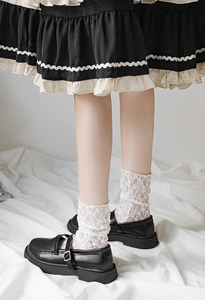 Close-up of white floral lace mid-calf socks paired with black Mary Jane platform shoes