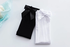Close-up of JK style knee high socks with large silk bows in black and white colors