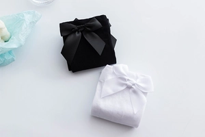 Detailed flat lay of white and black knee-high socks with elegant satin bow accents