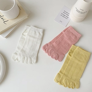 Flat lay of cotton five-toe socks in white, pink, and yellow with V-shaped mesh texture