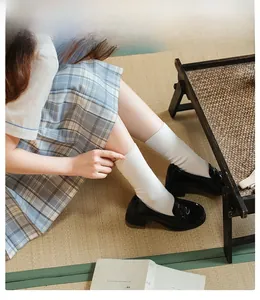 Calze bianche in pizzo stile giapponese con mocassini neri su un tappeto tatami