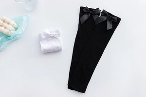 Detail showing high-elastic velvet knee socks with elegant satin bows in black and white