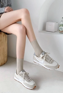 Close-up of beige ribbed crew socks paired with vintage suede panel sneakers