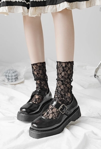 Detail of black lace mesh socks paired with platform Mary Jane shoes in a retro style