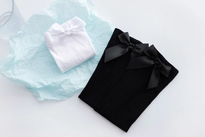 Detail of JK style velvet over-knee socks with delicate satin bow decorations on fabric