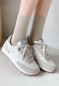 Close-up of retro off-white sneakers with grey suede panels and waffle rubber sole