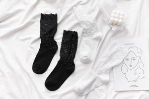 Vue à plat de chaussettes en dentelle noire et blanche aux motifs floraux ajourés
