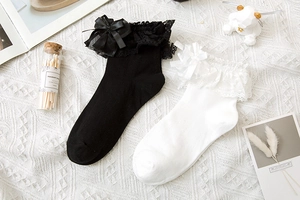 Dettaglio di calze in stile Lolita con bordo in pizzo e fiocchi di raso su tessuto