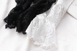 Gros plan sur des poignets en dentelle noirs et blancs aux motifs ajourés délicats