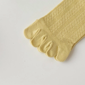 Macro detail of breathable knit mesh and toe separation on light yellow five-finger socks