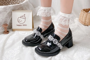 Détail de bas en dentelle blanche style Lolita avec des chaussures vernies noires à plateforme