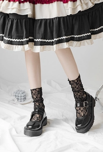 Detail of black lace mesh socks paired with patent leather Mary Jane platform shoes