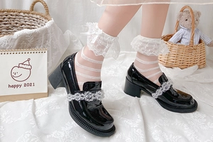 Détail de chaussettes blanches à dentelle et nœud avec chaussures noires vernies compensées