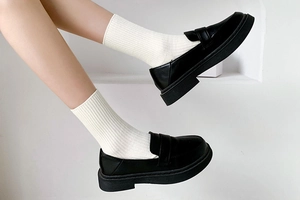 Close-up of black leather platform loafers paired with white ribbed mid-calf cotton socks