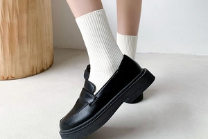 Side view of black platform loafers paired with white ribbed socks for an academic look