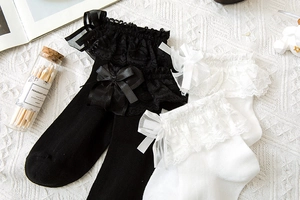 Dettaglio di calze Lolita con pizzo delicato e fiocchi di seta in bianco e nero