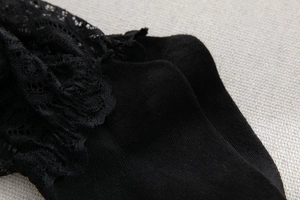Vue macro de la dentelle florale noire et de la maille sur ces chaussettes style Lolita