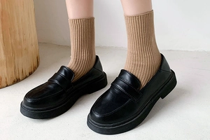 Close-up of black platform loafers paired with brown ribbed mid-calf crew socks