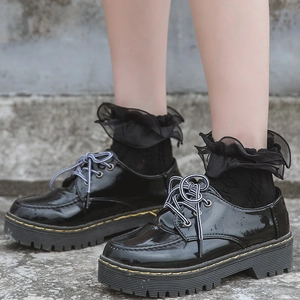 Black platform leather shoes with lace ruffle socks and distinctive yellow stitching
