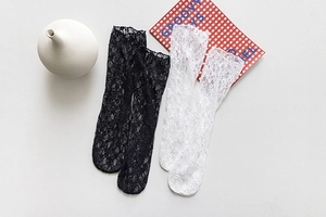 Detail of lace mesh mid-calf socks in black and white with delicate floral patterns
