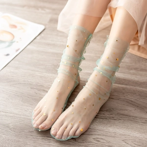 Detail of mint green sheer mesh socks with golden star patterns and ruffled cuffs