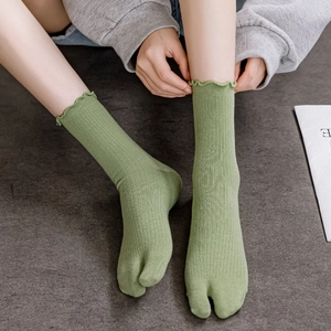 Detail of green Tabi socks with lettuce trim and ribbed texture worn with sandals