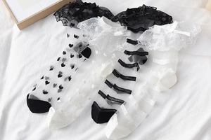 Détail de quatre chaussettes en résille Lolita avec dentelle et rubans sur tissu blanc